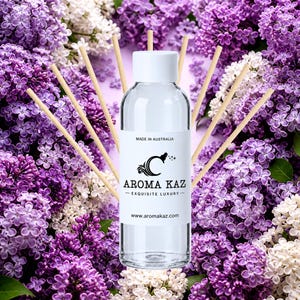 Pode incluir: Um frasco de vidro transparente com tampa branca e um rótulo branco com o texto MADE IN AUSTRALIA, AROMA KAZ, EXQUISITE LUXURY e www.aromakaz.com. O frasco está rodeado por vários palitos difusores de madeira de cor clara.
