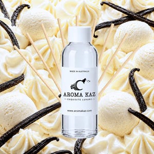 Könnte beinhalten: Eine durchsichtige Glasflasche für einen Raumduft mit weißem Verschluss und einem Etikett mit dem Text MADE IN AUSTRALIA, AROMA KAZ, EXQUISITE LUXURY und www.aromakaz.com, umgeben von hellen Holzstäbchen vor einem Hintergrund aus Vanilleschoten.