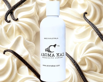 May include: A white cylindrical bottle with a cap, featuring black text that reads MADE IN AUSTRALIA, AROMA KAZ EXQUISITE LUXURY, and www.aromakaz.com. The bottle is surrounded by swirls of white cream and dark brown vanilla bean pods.