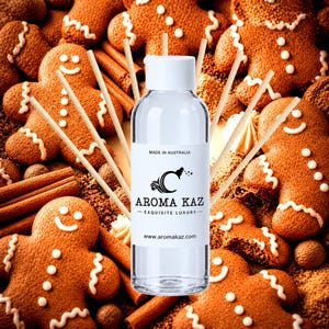 Op de afbeelding: Een doorzichtige plastic fles met een witte dop en een etiket met de tekst MADE IN AUSTRALIA AROMA KAZ EXQUISITE LUXURY www.aromakaz.com, omringd door verschillende dunne houten geurstokjes tegen een achtergrond van peperkoek.