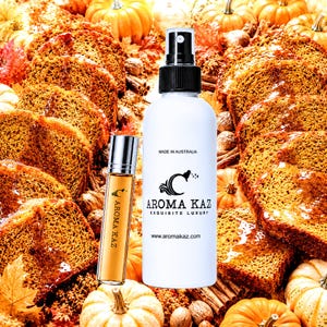 May include: A white spray bottle and a small glass roller bottle labeled AROMA KAZ EXQUISITE LUXURY with the text MADE IN AUSTRALIA and www.aromakaz.com. The bottles are positioned against a background of sliced pumpkin bread and pumpkins.
