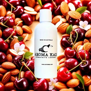 Könnte beinhalten: Eine weiße Flasche mit weißem Deckel, mit dem Text "AROMA KAZ EXQUISITE LUXURY" und "MADE IN AUSTRALIA". Die Flasche ist von frischen roten Kirschen, Mandeln und kleinen weißen Blüten umgeben. Die Website www.aromakaz.com ist ebenfalls sichtbar.