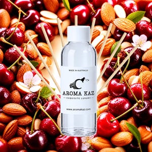 May include: A clear glass bottle with a white cap and a label reading AROMA KAZ, MADE IN AUSTRALIA, and www.aromakaz.com, surrounded by several thin wooden diffuser reeds against a background of scattered red cherries and brown almonds.