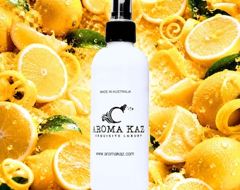 May include: A white spray bottle with a black cap, displaying the text "AROMA KAZ EXQUISITE LUXURY" and "MADE IN AUSTRALIA." The bottle is surrounded by fresh lemons and lemon slices.