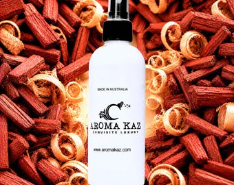 May include: A white spray bottle with a black cap, featuring the "Aroma Kaz" logo, sits against a backdrop of red wood chips and curls. The bottle is labeled "Made in Australia" and displays the website address.