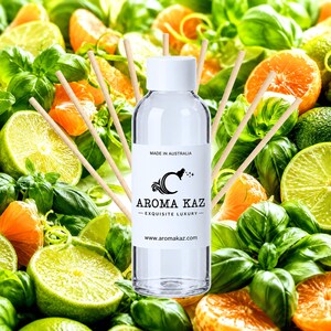 May include: A clear glass reed diffuser bottle with a white cap and a label reading MADE IN AUSTRALIA AROMA KAZ EXQUISITE LUXURY www.aromakaz.com, surrounded by several light-colored wooden diffuser reeds against a background of limes and oranges.