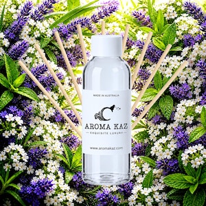 Könnte beinhalten: Eine durchsichtige Glasflasche für einen Raumduft mit weißem Verschluss und sechs Holzstäbchen. Das weiße Etikett zeigt den Text MADE IN AUSTRALIA, das Aroma Kaz Logo, den Text AROMA KAZ EXQUISITE LUXURY und die Website www.aromakaz.com in Schwarz.