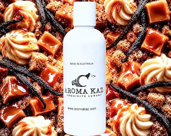 May include: A white cylindrical bottle with a screw-top cap featuring the black text MADE IN AUSTRALIA, the Aroma Kaz logo, the words AROMA KAZ EXQUISITE LUXURY, and the website www.aromakaz.com, centered over a background of caramel cubes and vanilla.