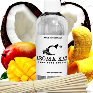 May include: A clear bottle with a white label featuring the text "AROMA KAZ EXQUISITE LUXURY" and "MADE IN AUSTRALIA" sits in front of a coconut half, mango, and banana. A bundle of wooden sticks is in the foreground.