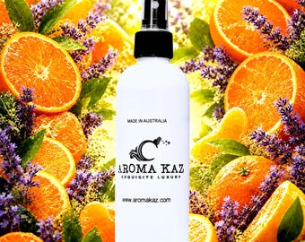 May include: White spray bottle with a black cap, featuring the "Aroma Kaz" logo, set against a backdrop of orange slices, lavender, and green leaves. The text "Made in Australia" and the website address are also visible.