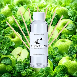 May include: A clear plastic bottle with a white cap and a label reading AROMA KAZ, MADE IN AUSTRALIA, and www.aromakaz.com, positioned in front of a background of green apples and fresh mint leaves with several thin wooden diffuser reeds.