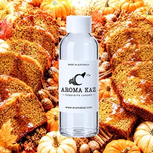 May include: A clear plastic bottle with a white cap and a white label featuring the text MADE IN AUSTRALIA, AROMA KAZ, EXQUISITE LUXURY, and www.aromakaz.com. The bottle is centred against a background of sliced pumpkin bread and small pumpkins.