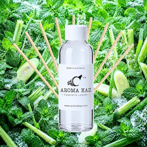 Puede incluir: Una botella de vidrio transparente con tapa blanca y una etiqueta blanca con el texto AROMA KAZ, EXQUISITE LUXURY, MADE IN AUSTRALIA y www.aromakaz.com, rodeada por varios palitos difusores de madera clara dispuestos en forma de abanico.