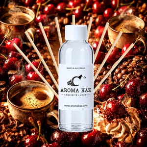 May include: A clear glass bottle with a white cap and a label reading MADE IN AUSTRALIA AROMA KAZ EXQUISITE LUXURY www.aromakaz.com, surrounded by several thin wooden diffuser reeds, positioned against a background of coffee and cherries.