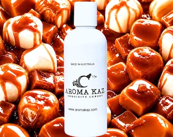 May include: A white cylindrical bottle with a cap, featuring the black text MADE IN AUSTRALIA, AROMA KAZ, EXQUISITE LUXURY, and www.aromakaz.com, positioned against a background of white marshmallows covered in a thick, glossy amber caramel sauce.