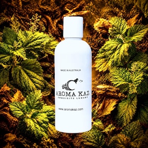 Op de afbeelding: Een witte cilindrische fles met een witte dop voorzien van zwarte tekst met de tekst MADE IN AUSTRALIA, AROMA KAZ, EXQUISITE LUXURY en www.aromakaz.com, samen met een zwart logo van een gestileerde letter C met sterretjes.
