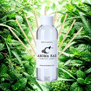 May include: A clear glass reed diffuser bottle with a white cap and a white label featuring the text AROMA KAZ, EXQUISITE LUXURY, MADE IN AUSTRALIA, and www.aromakaz.com. Several thin, light-colored wooden reeds fan out from behind the bottle.