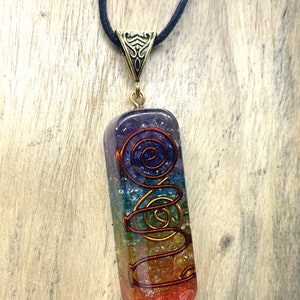 May include: A rainbow colored seven chakra crystal pendant with a gold wire spiral design. The pendant is on a black cord.