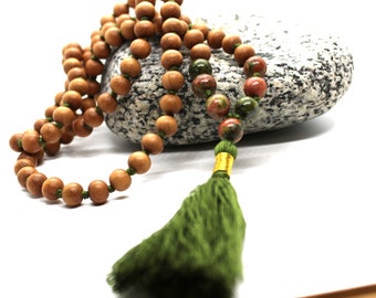 May include: A brown wooden mala bead necklace with green and red gemstone beads and a green tassel.