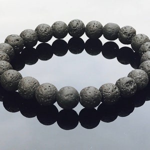 May include: A black lava rock beaded bracelet. The beads are round and have a rough, textured surface.