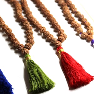 May include: Four brown beaded necklaces with tassels. The tassels are blue, green, red and purple.