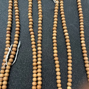 May include: Four strands of brown wooden beads, each strand is made up of round beads, all of the beads are the same size and shape.