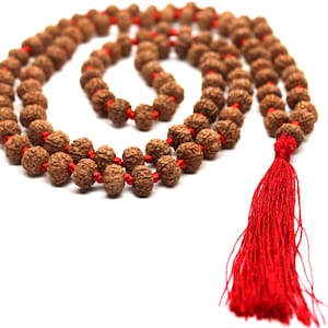 May include: A brown mala bead necklace with a red tassel. The beads are made of natural wood and are strung on a red cord.