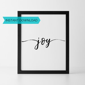 May include: A black framed print with the word "joy" written in cursive script on a white background.