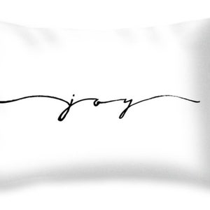 May include: White throw pillow with the word "joy" in black cursive script. The word is centered horizontally and slightly below the center of the pillow. The pillow has a soft, inviting appearance.