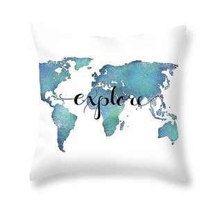 K&ouml;nnte beinhalten: Ein wei&szlig;es Kissen mit einer blauen Aquarell-Weltkarte und dem Wort "explore" in schwarzer Schrift.
