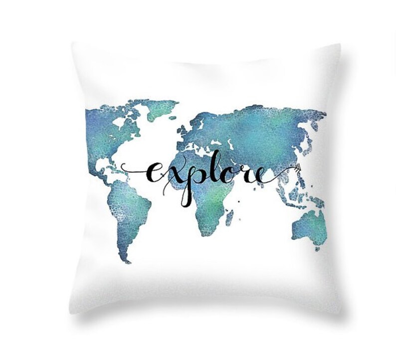K&ouml;nnte beinhalten: Ein wei&szlig;es Kissen mit einer blauen Aquarell-Weltkarte und dem Wort "explore" in schwarzer Schrift.
