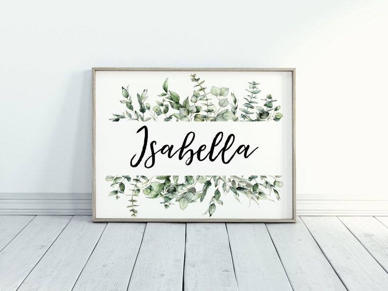 May include: A framed print with a white background and a watercolor illustration of green leaves. The name "Isabella" is written in black cursive lettering.
