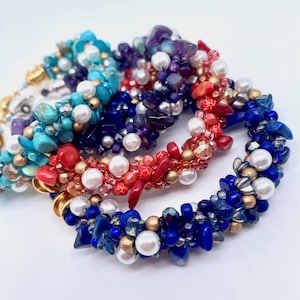 May include: A set of five colourful beaded bracelets featuring turquoise, purple, red, and blue beads. The bracelets are made with a variety of materials, including glass, metal, and coral.