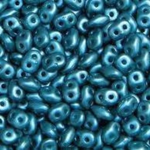 May include: A large quantity of teal blue seed beads. The beads are small and have a slightly irregular shape. They have a glossy finish.