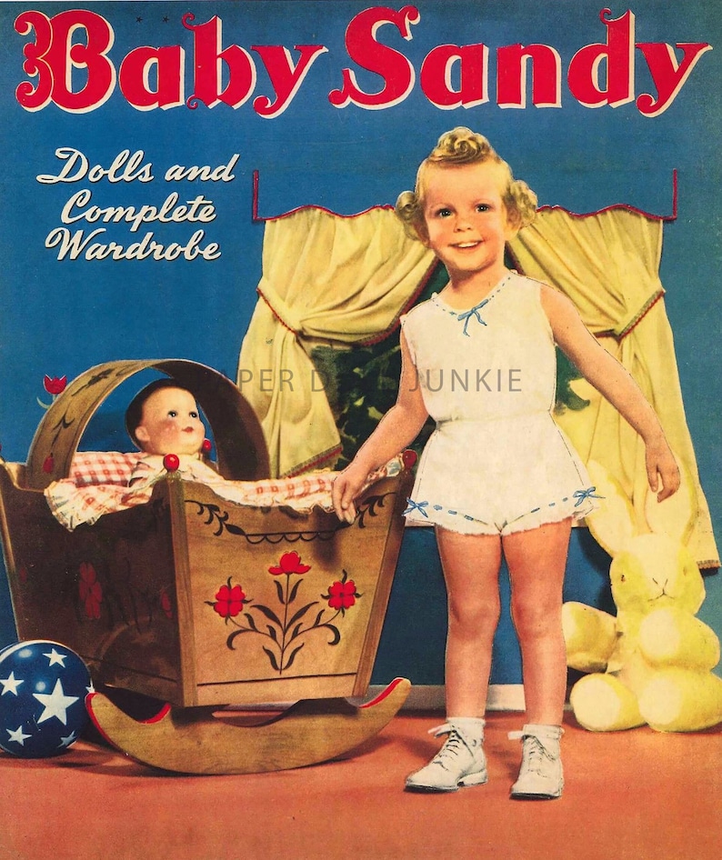 Może przedstawiać: Winietkowe ogłoszenie dla zestawu lalki i garderoby o nazwie "Baby Sandy". Reklama przedstawia młodą dziewczynkę w białej sukience trzymającą kołyskę z lalką w środku. Kołyska jest ozdobiona czerwonymi kwiatami i ma w środku kratkowany koc. Dziewczynka stoi na brązowej podłodze z ż&oacute;łtym pluszowym kr&oacute;likiem obok niej.