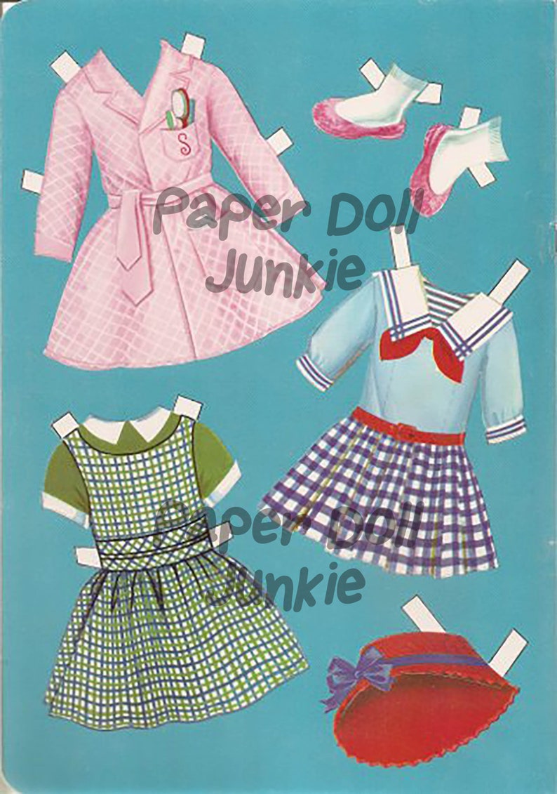 Puede incluir: Un conjunto de mu&ntilde;eca de papel con un abrigo rosa, un vestido de marinero azul y blanco, un vestido de cuadros verdes y blancos, un sombrero rojo y un par de zapatos rosas.