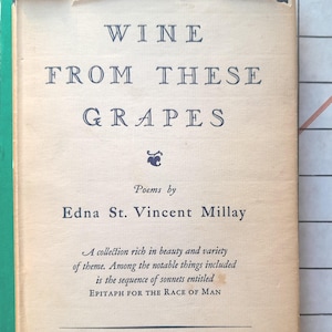 Puede incluir: Portada de libro antiguo de "Wine From These Grapes" de Edna St. Vincent Millay. La cubierta beige claro presenta texto azul oscuro. El título y el nombre del autor son prominentes. Publicado por Harper & Brothers en 1817.
