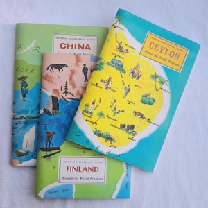 May include: Three vintage educational maps from the American Geographical Society's "Around the World Program". The maps are titled "China", "Ceylon", and "Finland". Each map features a colorful illustration of the country with key cities and geographical features labeled.