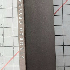 May include: A gray book with the text "STEUBEN CRYSTAL" printed on the spine.