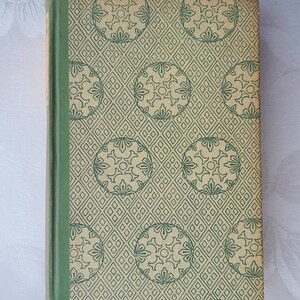 Op de afbeelding: Een groen en beige hardback boek met een herhalend patroon van groene cirkels en vierkanten op de omslag.
