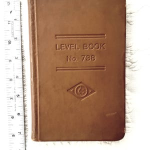 Może przedstawiać: Brązowy Level Book, nr 788, z wytłoczonym tekstem i logo w kształcie rombu. Książka ma około 18 cm wysokości, z linijką z boku. Okładka jest w jednolitym, średnio brązowym kolorze.
