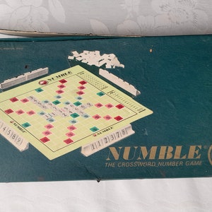 May include: A green box containing a game board. The game board is a crossword puzzle with numbers instead of letters. The box says "NUMBLE The Crossword Number Game".