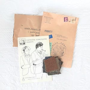 May include: An assortment of vintage stationery and fabric swatches. The image includes brown envelopes, a brochure with illustrations, and small fabric samples in various shades of brown and blue. The envelopes have text and stamps.