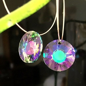May include: A pair of silver hoop earrings with iridescent crystal drops. The crystal drops are round and oval shaped and have a rainbow of colors.