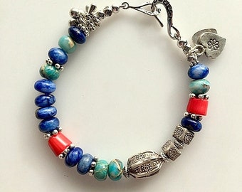 May include: A blue, turquoise, and red beaded bracelet with silver accents and a heart charm. The bracelet has a lobster clasp closure.