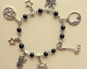 May include: A black beaded bracelet with silver charms, including a star, a sun, a moon, a pentagram, a fairy, and a figure holding a staff.