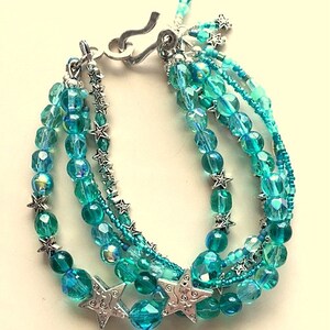 May include: Multi-strand bracelet with turquoise and silver beads. The bracelet features a silver clasp and star-shaped charms.