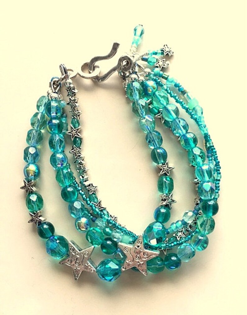 May include: Multi-strand bracelet with turquoise and silver beads. The bracelet features a silver clasp and star-shaped charms.
