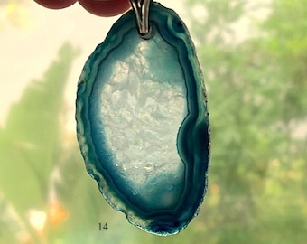 May include: A teal blue agate pendant with a silver bail. The agate has a white center and a layered pattern of blue and white.