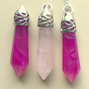 May include: Three silver pendant charms with pink and white agate stones. The charms are in the shape of a teardrop with a decorative silver top.